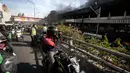 Seorang pengendara motor mengambil gambar kebakaran yang melanda Blok III Pasar Senen, Jakarta Pusat, Kamis (19/1). Banyak warga yang melintas melambatkan laju kendaraannya untuk melihat kebakaran Pasar Senen. (Liputan6.com/Faizal Fanani)