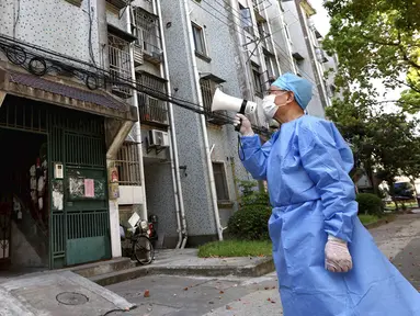 Seorang sukarelawan menggunakan megafon untuk berbicara dengan penduduk di sebuah gedung apartemen di Shanghai, China, 12 April 2022. Shanghai telah membebaskan lebih dari 6.000 orang lagi dari observasi medis di tengah wabah COVID-19. (Chen Jianli/Xinhua via AP)