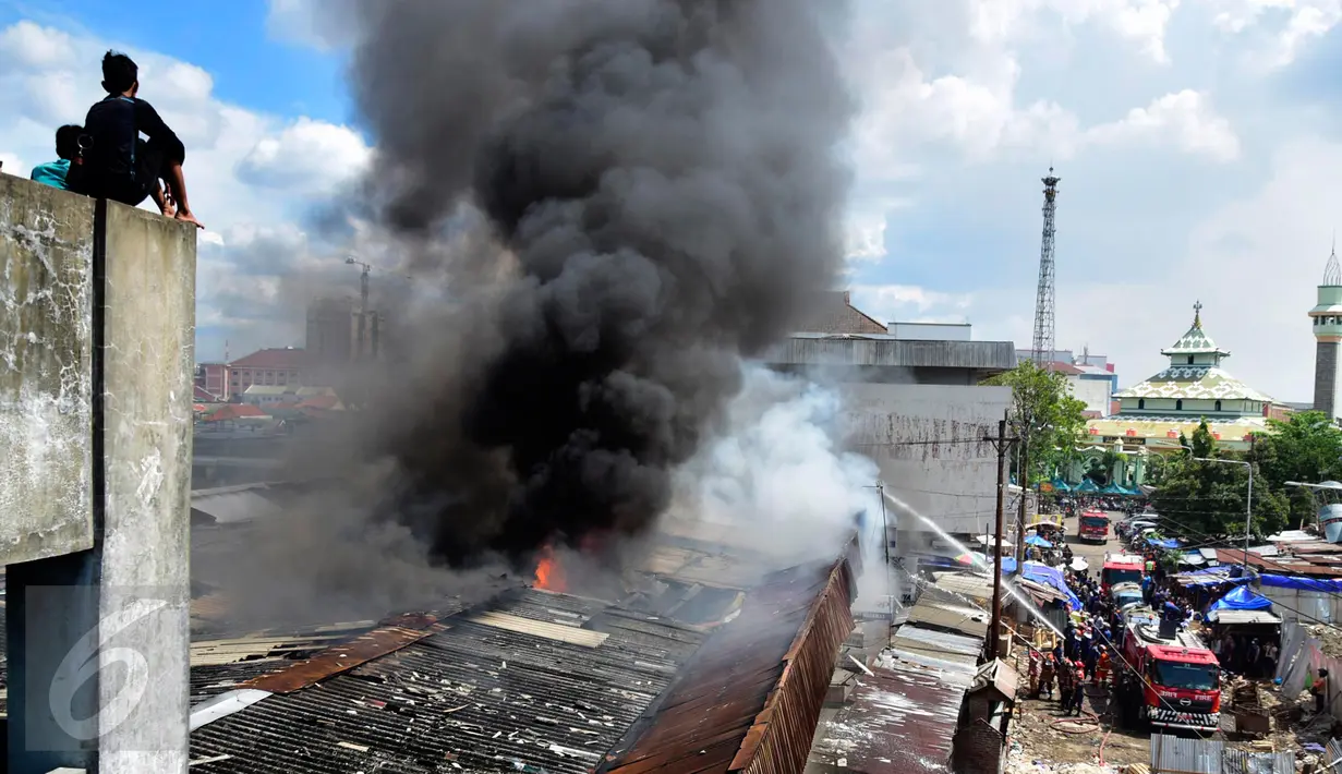 Asap hitam membumbung tinggi akibat kebakaran yang melanda Pasar Kanjengan Semarang yang masih satu kompleks dengan Pasar Johar, Sabtu (18/6). Sejumlah mobil pemadam kebakaran dikerahkan memadamkan belasan toko di kompleks pasar itu. (Liputan6.com/Gholib)