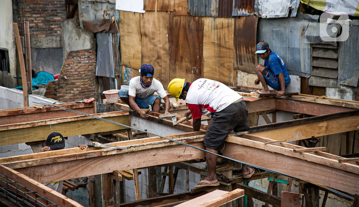 Para pekerja menyelesaikan pembangunan rumah panggung di dekat bantaran Kali Ciliwung, Kampung Melayu, Jakarta, Rabu (7/4/2021). Pemerintah Provinsi DKI Jakarta melakukan renovasi terhadap 40 hunian warga Kampung Melayu menjadi rumah panggung. (Liputan6.com/Faizal Fanani)