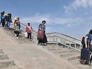 Wisatawan melintasi tangga tanggul laut yang telah selesai dibangun di Pelabuhan Kali Adem, Muara Angke, Jakarta, Selasa (12/2). Pembangunan tanggul laut tersebut memiliki tinggi 4 meter. (Merdeka.com/Iqbal S. Nugroho)