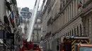 Petugas pemadam berusaha memadamkan api yang membakar lantai atas Hotel Ritz, Paris, Selasa (19/1). Enam puluh petugas pemadam kebakaran dan 15 mobil pemadam kebakaran dikerahkan untuk memadamkan api.  (AFP PHOTO/Lionel Bonaventure)