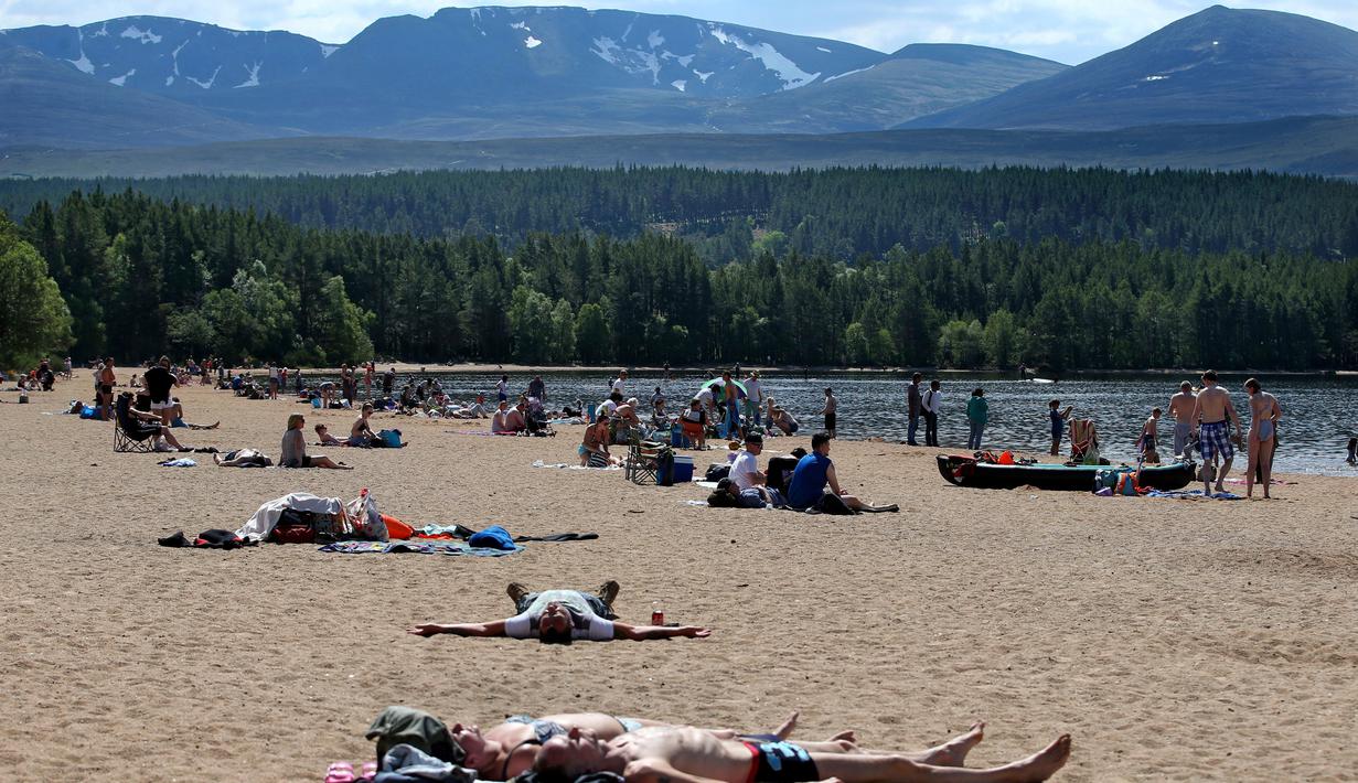 Orang-orang berjemur di pantai di Loch Morlich dekat Aviemore, di Skotlandia, (28/5). Cuaca panas tengah melanda sebagian besar wilayah di Inggris. (AP Photo/Jane Barlow)