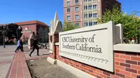 Orang-orang berjalan melintasi papan tanda di wilayah University Village di University of Southern California di Los Angeles pada 12 Maret 2019. (Foto: AP)