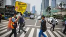 Relawan yang tergabung dalam Gerakan Mahasiswa Cegah Covid-19 membawa poster 'Ayo Lawan Corona' saat kampanye di Pelican Cross kawasan Thamrin, Jakarta, Senin (23/3/2020). (Liputan6.com/Faizal Fanani)