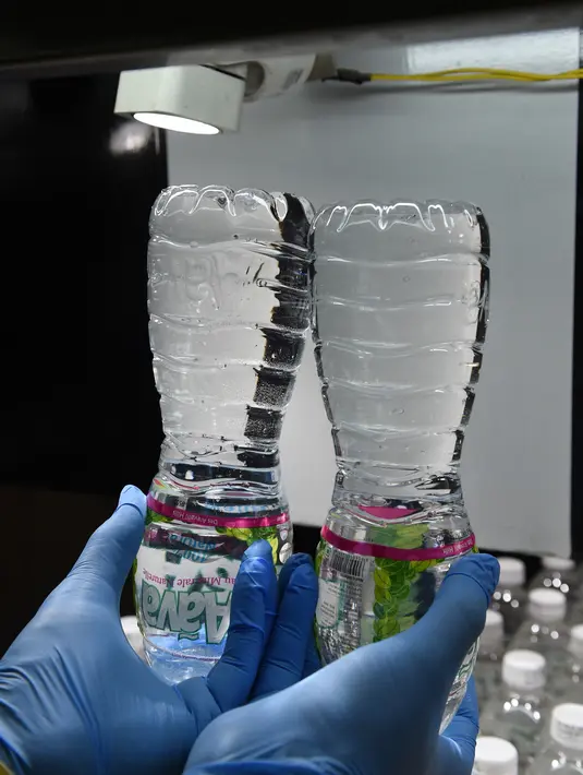Seorang teknisi memeriksa botol air mineral Aava di Ahmedabad, India (19/3). Hari Air Sedunia jatuh pada tanggal 22 Maret dan berfokus pada pentingnya akses universal terhadap air bersih, sanitasi dan fasilitas kebersihan. (AFP Photo/Sam Panthaky)