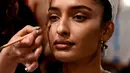 Seorang model India saat dirias oleh kru makeup di belakang panggung sebelum tampil di catwalk selama Lakmé Fashion Week (LFW) Summer Resort 2019 di Mumbai, India (31/1). (AFP Photo/Sujit Jaiswal)