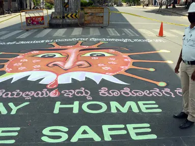Petugas kepolisian India berdiri disamping grafiti yang mengilustrasikan virus  corona di Bangalore (3/4/2020). Grafiti tersebut dibuat untuk meningkatkan kesadaran masyarakat agar mematuhi lockdown yang diberlakukan pemerintah India  sebagai langkah pencegahan COVID-19. (Xinhua/Stringer)