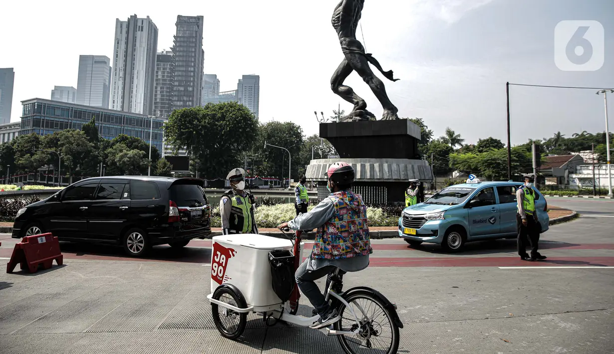 Pedagang melintas saat polisi berjaga di tempat penyekatan PPKM Darurat di kawasan Ratu Plaza, Jakarta, Sabtu (17/7/2021). Menko PMK Muhadjir Effendy mengabarkan Pemberlakuan Pembatasan Kegiatan Masyarakat (PPKM) Darurat akan diperpanjang hingga akhir Juli. (Liputan6.com/Faizal Fanani)