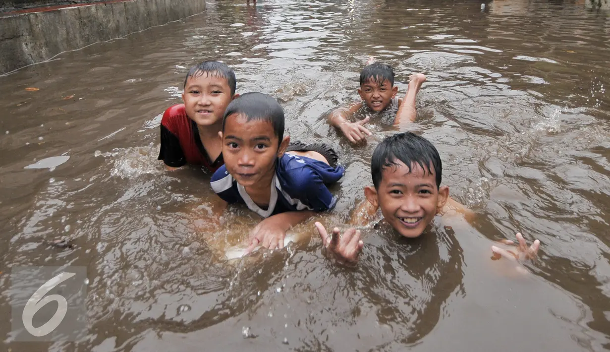 Sejumlah anak di kawasan Kemang Utara memanfaatkan banjir untuk bermain, Jakarta, Rabu (20/7). Akibat intensitas hujan deras yang mengguyur Jakarta, sejumlah ruas jalan tergenang air. (Liputan6.com/Yoppy Renato)