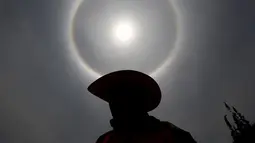 Seorang pria mengunakan topi saat berada di bawah 'Halo Matahari' di Mexico City, Kamis (21/5/2015). Menurut ahli meteorologi, fenomena cuaca menciptakan pelangi mengelilingi matahari dan dibentuk oleh refleksi dari kristal es. (REUTERS/Edgard Garrido)