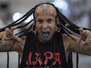 Seniman tato asal Brasil, Dark Virus berpose memamerkan tato, tindikan, dan lidahnya yang dimodifikasi dalam acara Sao Paulo Tattoo Week, Brasil, Jumat (25/10/2019). Sao Paulo Tattoo Week adalah acara tahunan yang diikuti pecinta tato dari seluruh dunia. (AP Photo/Andre Penner)