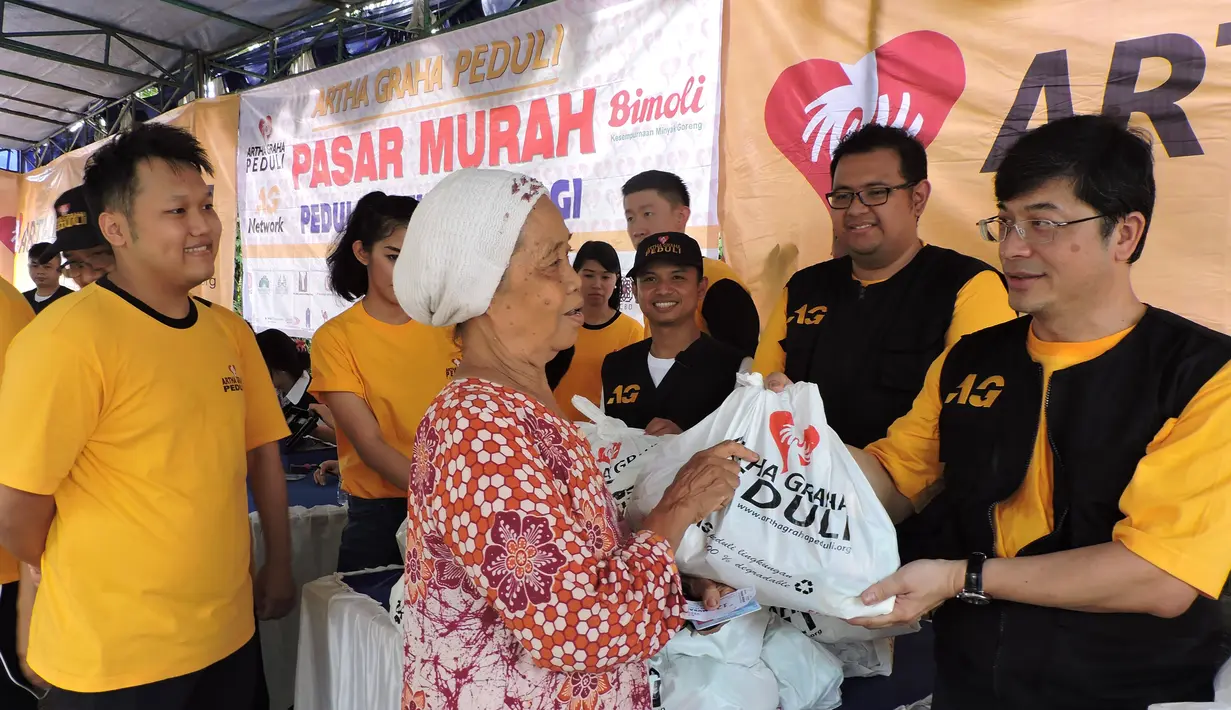 Koordinator Pasar Murah Artha Graha Peduli Jet Soedirdja, menyerahkan langsung paket sembako murah kepada warga di dampingi oleh Ketua Pelaksana Pasar Murah Arviano Sahar (sebelah kiri), Jakarta, Minggu (24/1/2014). (Media Center AGN - AGP)