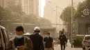 Orang-orang yang memakai masker wajah berjalan di sepanjang jalan saat badai pasir di ​Beijing, China, Kamis (6/5/2021). Debu dan badai pasir akhir musim semi mengirim indeks kualitas udara melonjak di Ibu Kota China pada hari ini. (AP Photo/Mark Schiefelbein