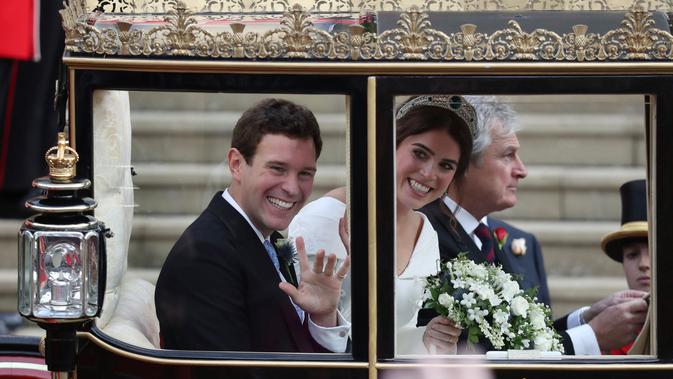 Putri Eugenie dan Jack Brooksbank menyapa mesyarakat saat menaiki kereta kencana usai melangsungkan pernikahan di Kapel St. George, Windsor Castle, London, Inggris,  Jumat (12/10). (Andrew Matthews, Pool via AP)