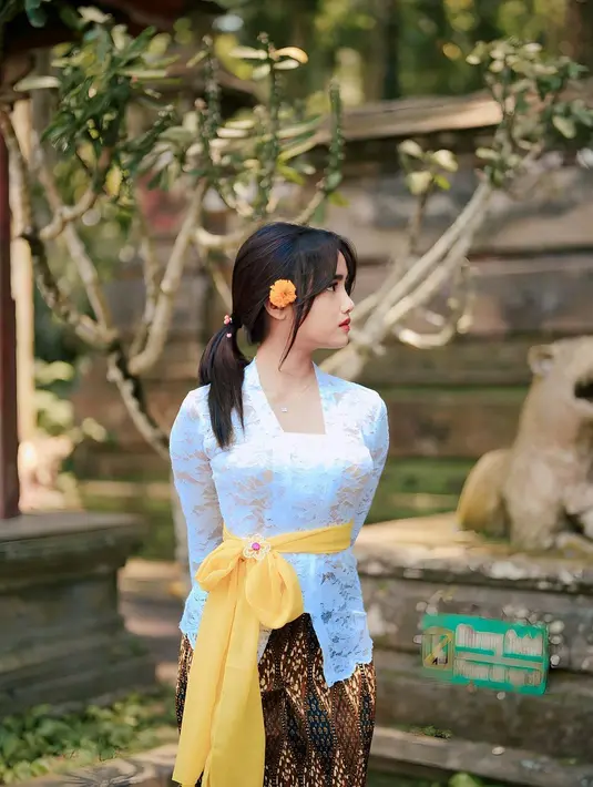 Di foto ini, Fuji mengenakan kebaya putih, dipadukan dengan kain batik cokelat, dan sneakers putih. Penampilannya semakin menarik dengan selendang kuning dan bunga yang disematkannya di salah satu telinganya. [Foto: Instagram/fuji_an]