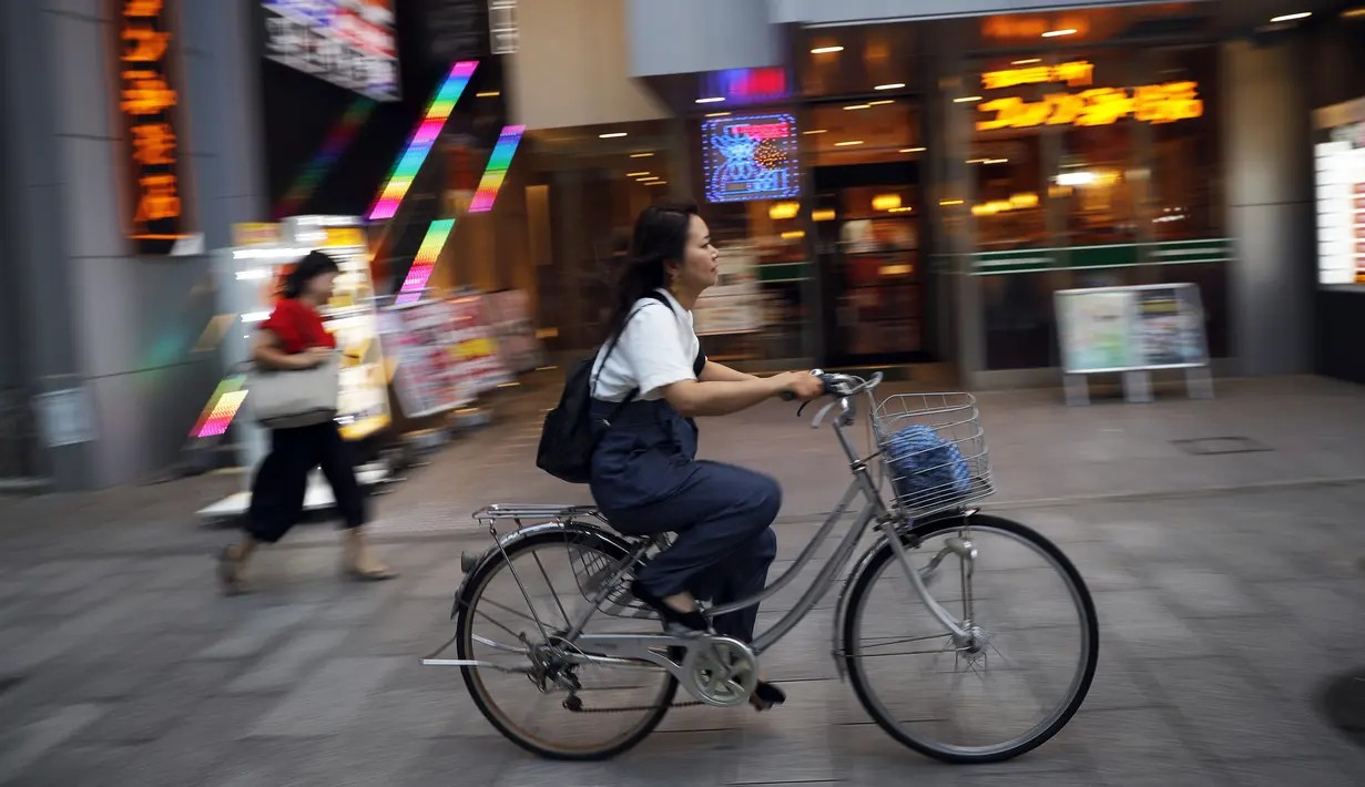 Seorang wanita mengendarai sepedanya di sebuah jalan di Nagoya, Jepang (24/9/2019). Kota Nagoya terletak di Daratan rendah Nōbi, bagian barat daya Prefektur Aichi. (AP Photo/Christophe Ena)