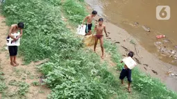 Anak-anak berjalan di pnggir Sungai Ciliwung, Jatinegara, Jakarta Timur, Sabtu (4/7/2020). Minimnya lahan bermain menyebabkan anak-anak tersebut bermain tidak pada tempatnya, meski dapat membahayakan keselamatan. (Liputan6.com/Immanuel Antonius)