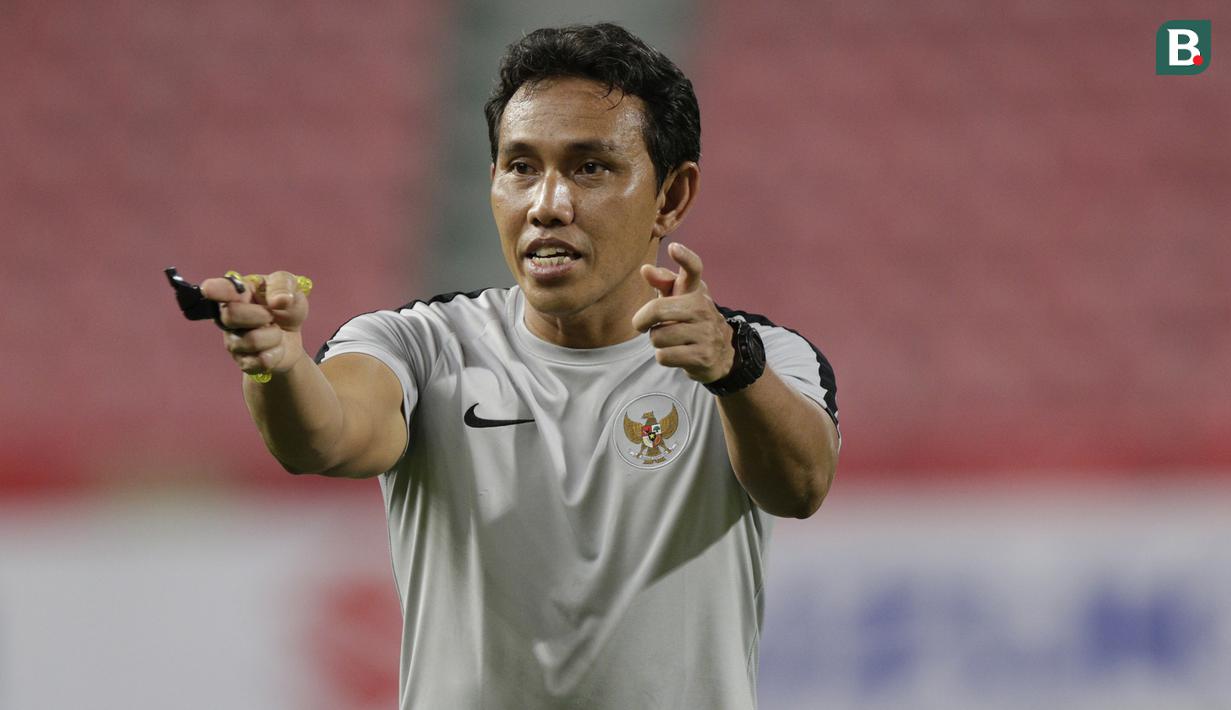 Pelatih Timnas Indonesia, Bima Sakti, memberikan arahan kepada anak asuhnya saat latihan di Stadion Rajamangala, Bangkok, Jumat, (16/11). Latihan ini persiapan jelang laga Piala AFF 2018 melawan Thailand. (Bola.com/M. Iqbal Ichsan)