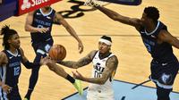 Guard Utah Jazz, Jordan Clarkson, berusaha menembak di antara pemain Memphis Grizzlies, Ja Morant dan Jaren Jackson Jr.pada paruh kedua pertandingan keempat babak play-off NBA, Selasa (1/6/2021) pagi WIB. (AP Photo/Brandon Dill)