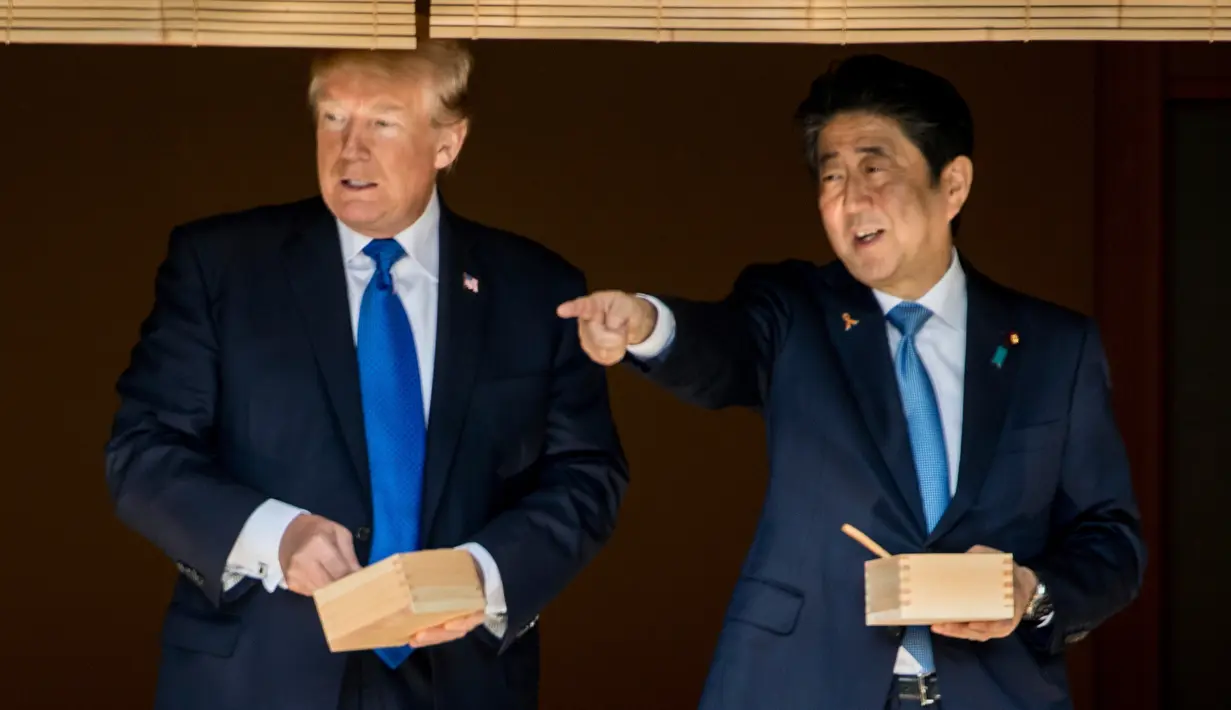 Presiden AS Donald Trump dan PM Jepang Shinzo Abe berbincang sambil memberi makan ikan di kolam koi Istana Akasaka, Tokyo, Senin (6/11). Beragam momen terlihat dalam kunjungan Presiden Donald Trump ke Jepang. (AP/Andrew Harnik)