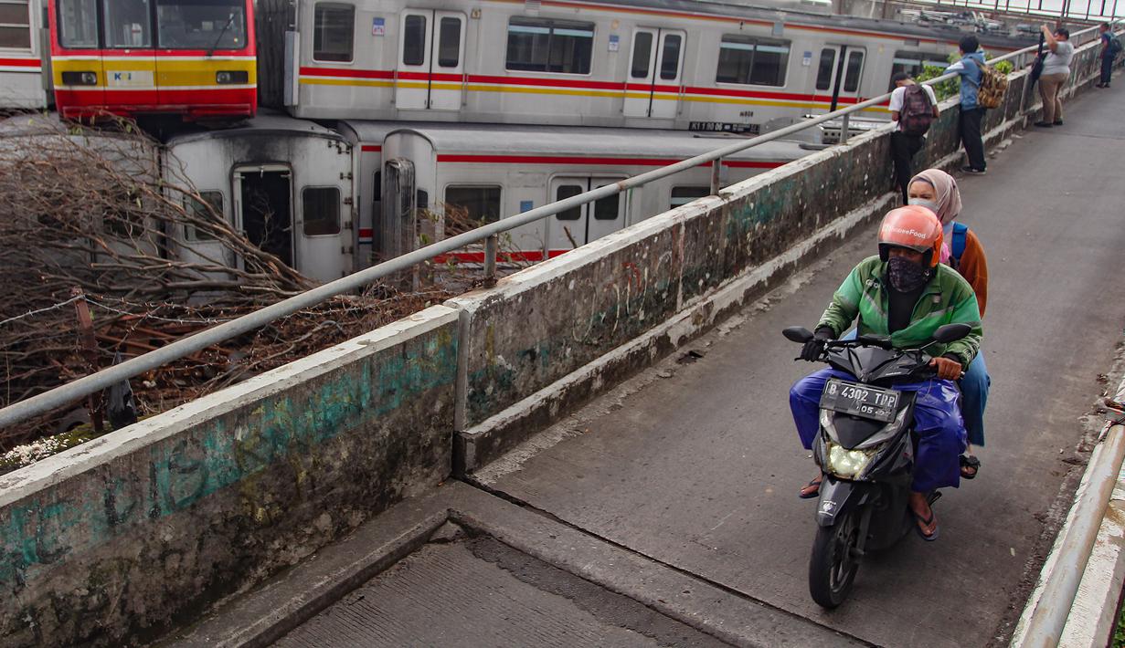 Tumpukan sarana transportasi umum itu terlihat jelas dari jembatan Jalan Terusan Dipo. Tampak dalam foto, warga melintas di jalan layang dekat Depo Kereta Rel Listrik (KRL) di Jalan Kampung Rawageni, Cipayung, Kota Depok, Jawa Barat, Selasa (20/01/2026). (Merdeka.com/Arie Basuki)
