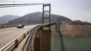 Sebuah mobil melewati Jembatan Bidwell Bar di Danau Oroville saat ketinggian air masih rendah akibat kondisi kekeringan yang terus berlanjut di Butte County, California, Minggu (228/2021). Kekeringan ekstrem di California telah membuat ketinggian air di danau itu terus menurun. (AP Photo/Ethan Swope