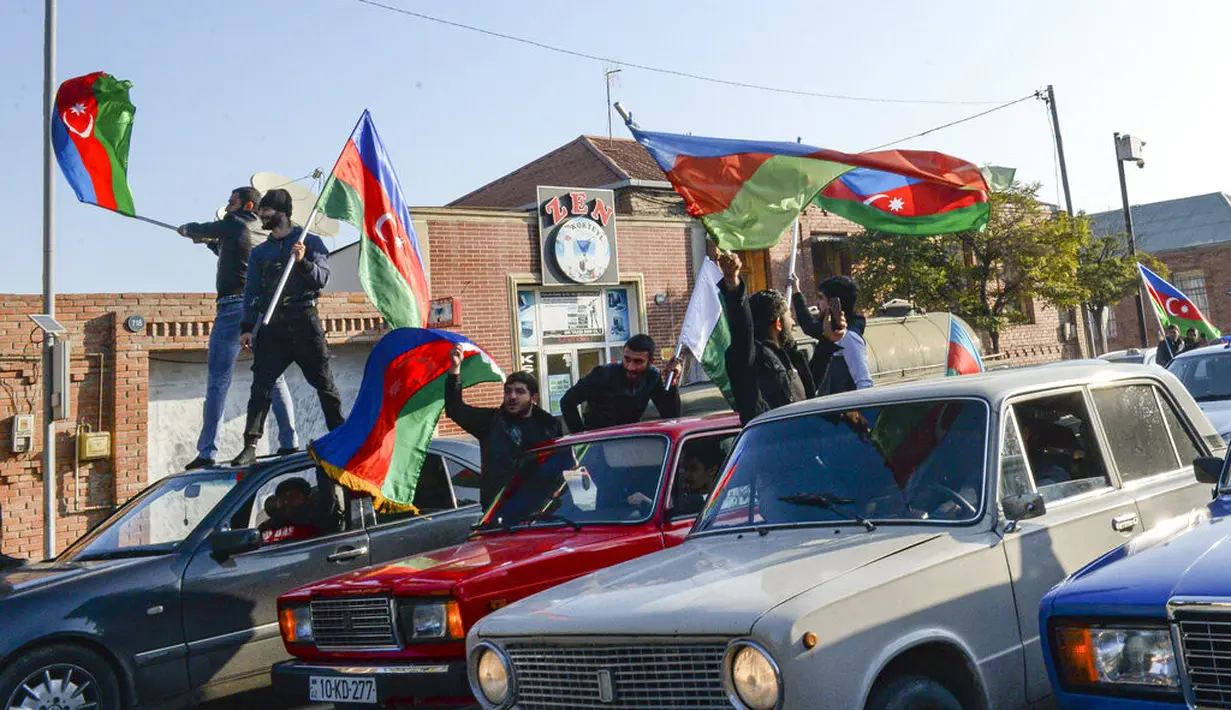 Rakyat Azerbaijan mengibarkan bendera nasional di Ganja, Azerbaijan, Selasa (10/11/2020). Armenia dan Azerbaijan mengumumkan perjanjian damai untuk menghentikan pertempuran atas wilayah Nagorno-Karabakh di Azerbaijan berdasarkan pakta yang ditandatangani dengan Rusia. (AP Photo/Aydin Mammedov)