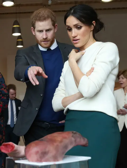 Pangeran Harry dan Meghan Markle melihat beberapa anggota tubuh buatan atau prostetik di Catalyst Inc, Belfast, Irlandia Utara, Jumat (23/3). Dalam kunjungannya, mereka juga menemui beberapa pengusaha muda Irlandia Utara. (Niall Carson/Pool via AP)