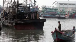 Dua orang lelaki melihat kapal yang terbakar di Pelabuhan Muara Angke, Jakarta, Jumat (27/2/2015). Diduga kebakaran disebabkan korsleting listrik. Kerugian ditaksir mencapai ratusan juta. (Liputan6.com/Johan Tallo)