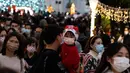 Seorang anak yang mengenakan pakaian pesta terlihat saat orang-orang berkumpul selama Natal di distrik budaya West Kowloon di Hong Kong (25/12/2021). Pohon Natal raksasa didekorasi secara glamor dengan karangan bunga dan ornamen, berkilauan dengan lampu meriah yang cerah. (AFP/Bertha Wang)