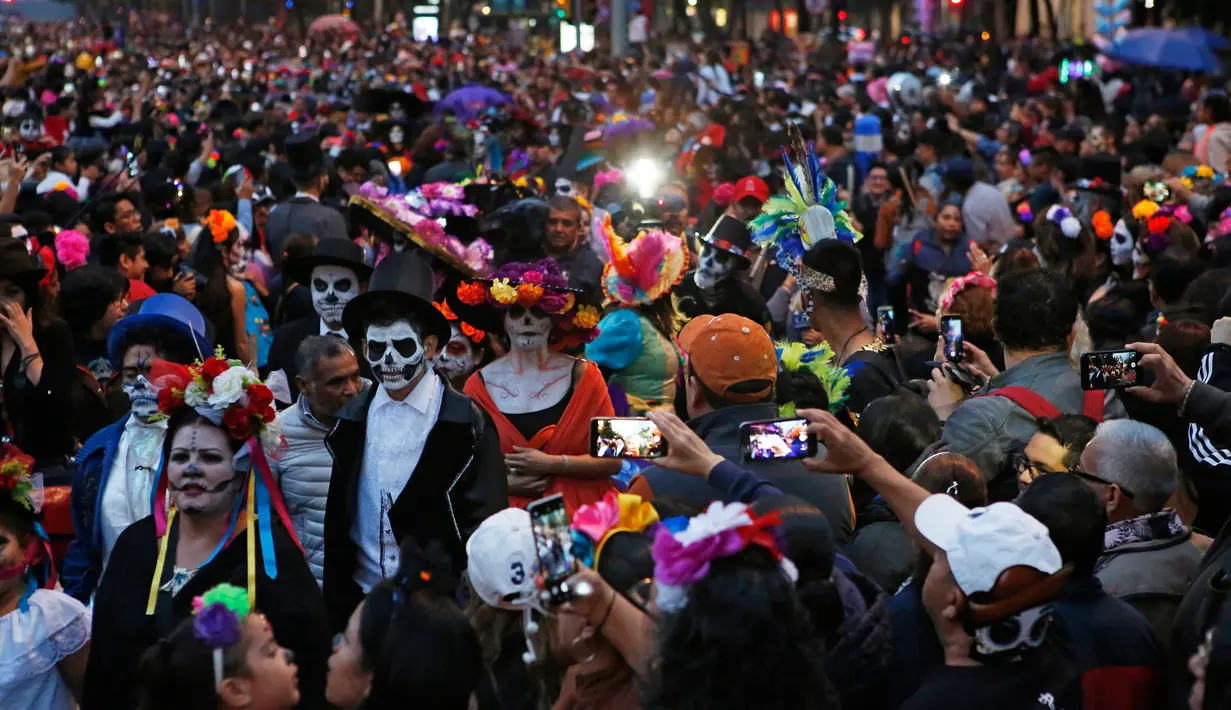 Suasana saat peserta yang berdandan ala tengkorak saat mengikuti parade Hari Orang Mati di Mexico City, Meksiko, Sabtu (26/10/2019. Para peserta dalam parade ini mengenakan kostum dan melukis wajah mirip dengan tokoh tengkorak Meksiko yang ikonik, Catrina. (AP Photo/Ginnette Riquelme)