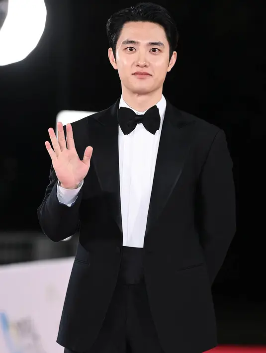 D.O EXO tampil tak kalah gagah dengan setelan jas dan celana panjang hitam, kemeja putih dilengkapi dengan dasi kupu-kupu hitam. [Foto: soompi.com]
