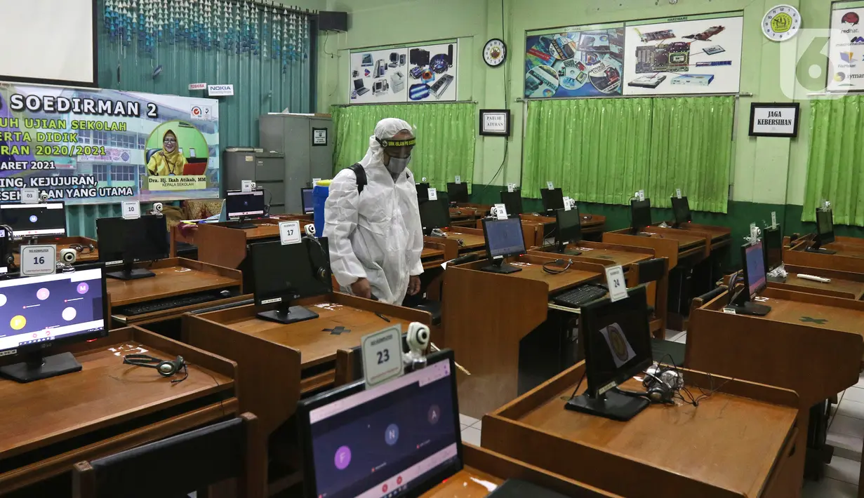 Petugas melakukan penyemprotan cairan disinfektan jelang dibukanya pembelajaran tatap muka di SMK PB Soedirman 2, Jakarta, Selasa (6/4/2021). Pemprov DKI Jakarta akan melakukan uji coba pembelajaran tatap muka di 100 sekolah mulai 7 April hingga 29 April 2021. (Liputan6.com/Herman Zakharia)