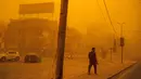 Seorang pejalan kaki berjalan di sepanjang jalan di tengah badai debu berat di Baghdad, Irak, Senin (16/5/2022). (Sabah ARAR/AFP)