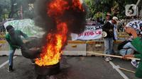 Sejumlah elemen mahasiswa menggelar demo dengan membakar ban bekas di kawasan Patung Kuda, Jakarta Pusat, Selasa (13/9/2022). Demo tersebut untuk menolak kebijakan pemerintah menaikkan harga bahan bakar minyak (BBM). (Liputan6.com/Johan Tallo)