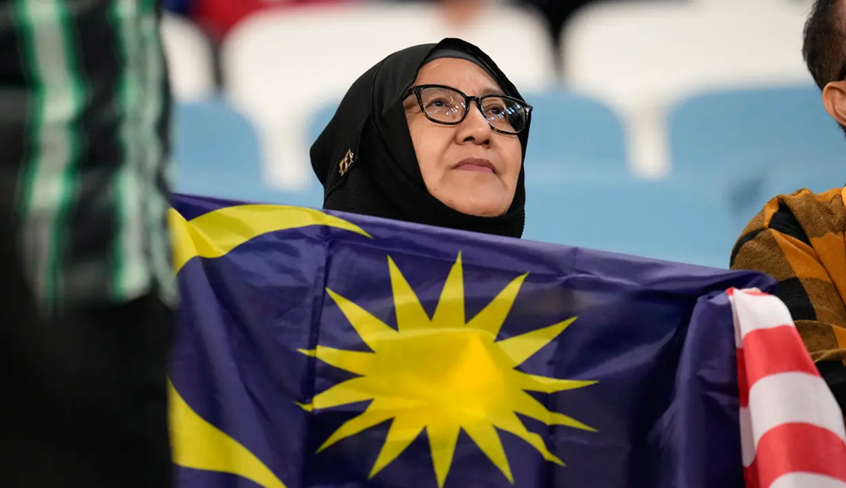 <p>Seorang suporter memegang bendera Malaysia jelang pertandingan sepak bola Grup E Piala Asia antara Malaysia dan Yordania di Stadion Al Janoub, Al Wakrah, Qatar, Senin (15/1/2024). (AP Photo/Aijaz Rahi)</p>