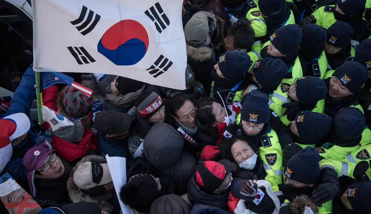 Demonstran anti-Korea Utara terlibat saling dorong dengan polisi saat melakukan aksi menyambut kedatangan kapal feri Korea Utara yang membawa rombongan seni yang akan tampil di Olimpiade Musim Dingin Pyeongchang 2018, Korea Selatan (6/2). (AFP/Ed Jones)