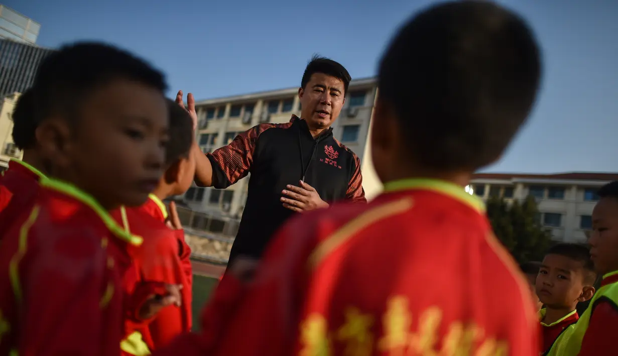 Mantan penyerang Manchester United, Dong Fangzhuo berbicara dengan anak-anak saat melatih di Xiamen di provinsi Fujian, China (10/12/2019). Dong Fangzhuo yang kini berusia 34 tahun melatih anak-anak di China, beberapa di antaranya berkebutuhan khusus. (AFP/Hector Retamal)