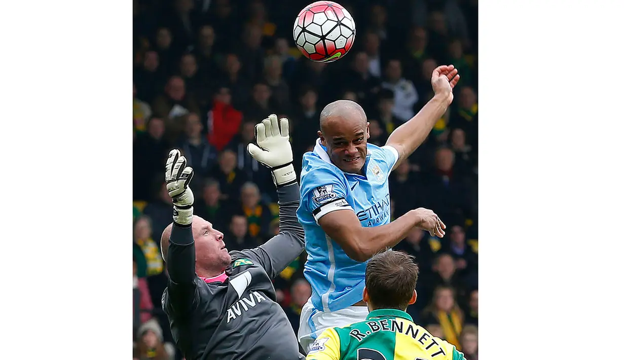 Pemain Manchester City, Vincent Kompany (tengah) berusaha menyundul bola dari hadangan kiper Norwich, John Ruddy (kiri) pada lanjutan liga Inggris pekan ke-30 di Stadion Carrow Road, Norwich, Sabtu (12/3/2016). (AFP/Lindsey Parnaby)