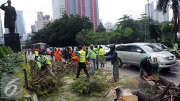 Sejumlah petugas mengevakuasi pohon tumbang di jalan Jenderal Sudirman, Jakarta, Senin (1/2). Pohon tumbang yang terjadi saat hujan deras mengakibatkan kemacetan panjang dikawasan tersebut. (Liputan6.com/Helmi Afandi)