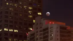 Bulan yang sedang memerah dipadukan dengan lansekap gedung-gedung tinggi terlihat di Los Angeles, California, Sabtu (4/4/2015). (David McNew/Getty Images/AFP)