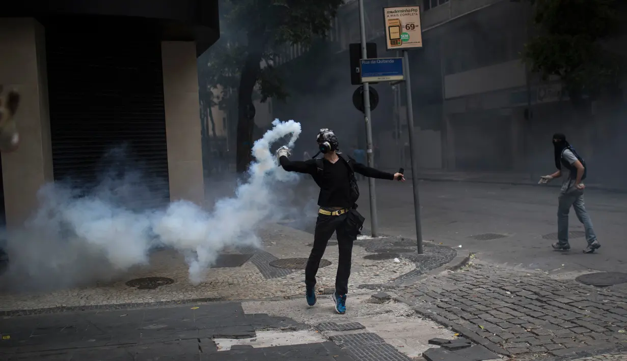Seorang pengunjuk rasa melemparkan gas air mata ke arah polisi saat memprotes rencana pembatasan belanja publik di Rio de Janeiro, Brasil, (9/2). (AP Photo/Felipe Dana)