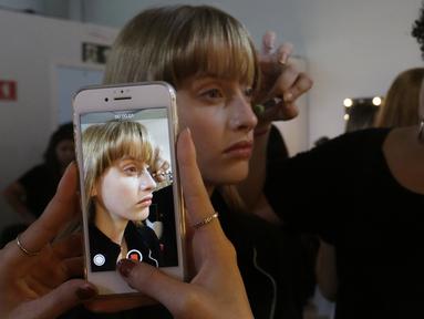 Model saat dirias wajahnya di belakang panggung sebelum tampil membawakan busana koleksi Beira selama Sao Paulo Fashion Week di Sao Paulo, Brasil (16/10/2019). SPFW ke-48 akan berlangsung hingga 18 Oktober.  (AP Photo / Nelson Antoine)