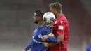 Pemain Union Berlin, Florian Huebner, berebut bola dengan pemain Schalke, Ahmed Kutucu, pada laga Bundesliga di Weserstadion Minggu (7/6/2020). Kedua tim bermain imbang 1-1. (AP/Michael Sohn)