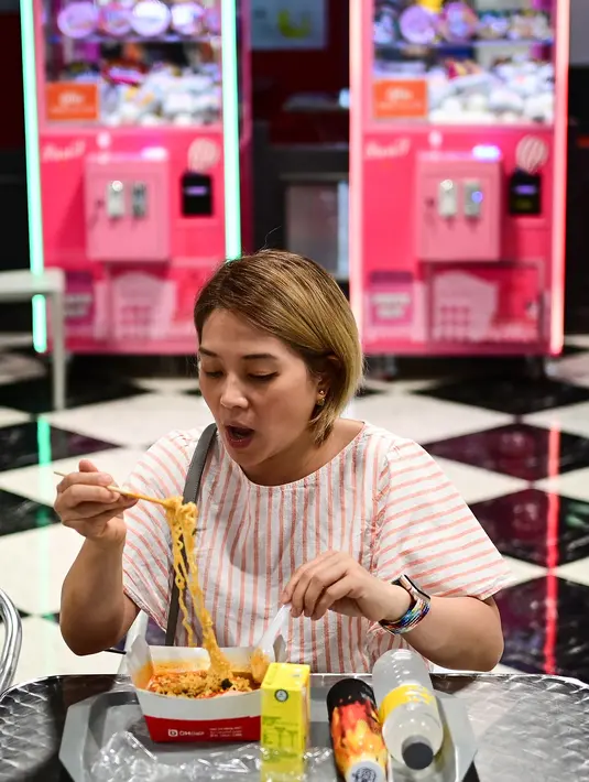 Seorang wanita makan mie instan untuk makan siang di toko Good Noodle yang menjual berbagai macam mie instan dari seluruh Asia, di Bangkok (25/8/2022). Thailand akan menaikkan harga mie instan Thailand, kata departemen perdagangan 24 Agustus menandai kenaikan harga pertama pada kebutuhan pokok harian dalam 14 tahun. (AFP/Vatsyayana)