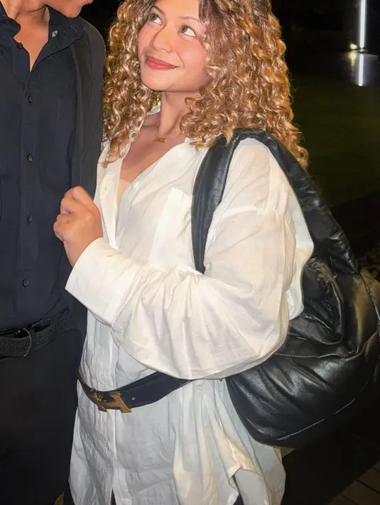 Amel melengkapi penampilannya dengan kemeja oversize, sabuk hitam sebagai aksen, dan celana pendek hitam, membuat gaya Carrie Bradshaw versi Amel ini terlihat begitu autentik.  [@amelcarla].