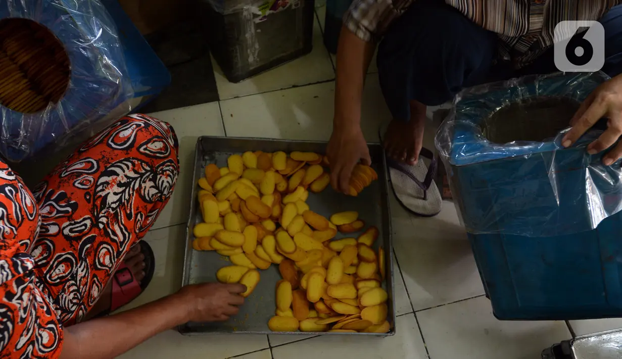 Pekerja memasukkan kue kering yang sudah matang ke dalam wadah kaleng di usaha pembuatan kue Pusaka Kwitang di kawasan Kwitang, Jakarta Pusat, Selasa (27/4/2021). Kue kering yang diproduksi antara lain putri salju, kastengel, nastar, kue lidah kucing, dan kue kacang. (merdeka.com/Imam Buhori)