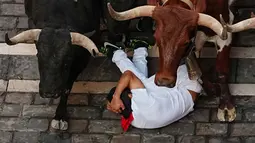 Seorang pengunjung festival terjatuh di depan banteng-banteng aduan Victoriano del Río saat acara lari banteng ketiga di festival San Fermín di Pamplona, Spanyol, Kamis, 9 Juli 2026. (AP Photo/Miguel Oses)