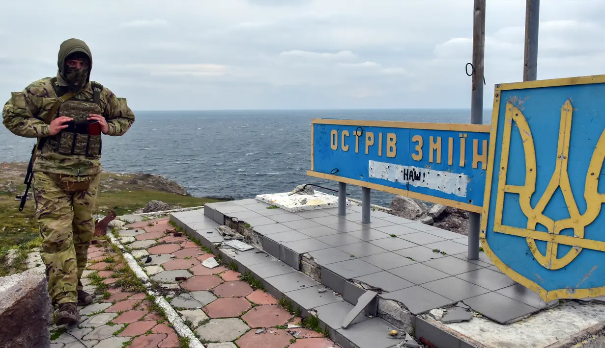 Seorang tentara Ukraina berjalan melewati tanda "Pulau Ular, milik kita" di Pulau Ular, Laut Hitam, Ukraina, 18 Desember 2022. Pasukan Rusia menduduki pulau itu pada awal-awal invasinya ke Ukraina, namun akhirnya mundur beberapa bulan kemudian. (AP Photo/Michael Shtekel)